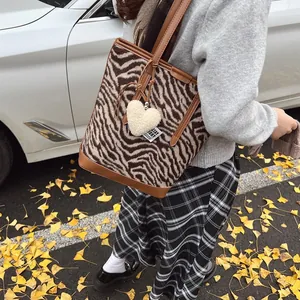 Brown zebra print tote bag with heart charm and leather strap in an autumn setting