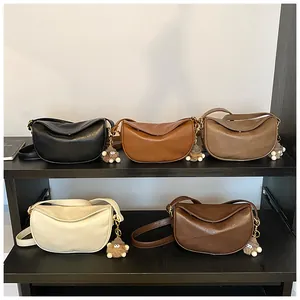 Close-up of crescent shoulder bags in five colors with cute plush pendants on a display rack