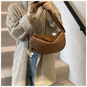 Detailed view of a brown faux leather dumpling bag with soft textures and plush charm