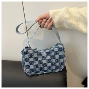 Close-up of blue and white checkered denim bag with distressed edges and faux leather strap