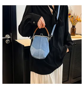 Detail of light blue denim shell bag featuring a wooden handle and metallic clasp closure