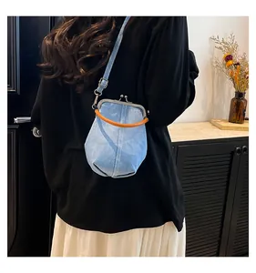 Detail view of light blue denim shell bag with orange handle and retro metal clasp
