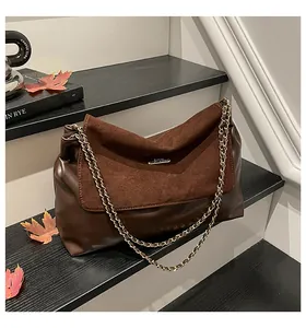 Detail of dark brown chain shoulder bag with gold hardware on autumn maple leaves