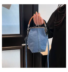 Detail of light blue denim shell bag with white stitching and silver metal kiss-lock