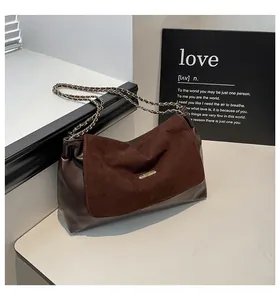 Detail of the brown dual-material leather handbag with gold chain strap and metal logo plate