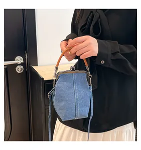 Close-up of blue denim shell bag featuring vintage metal clasp and white stitching detail