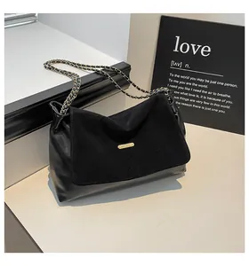 Close-up of black leather handbag featuring suede patchwork and gold chain strap