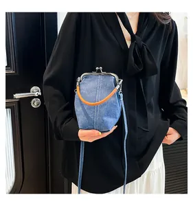 Close-up of vintage blue denim shell bag with silver kiss-lock and brown leather handle