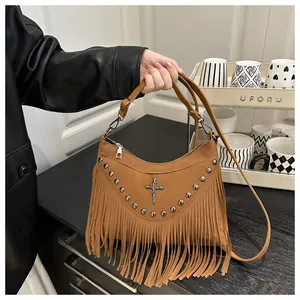 Close-up of brown suede punk crossbody bag with silver rivets, tassels, and a skull cross charm
