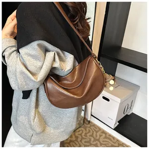 Side view of vintage brown moon-shaped bag with plush ball charm and wrinkled texture