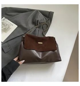Detail of two-tone brown leather shoulder bag with gold chain and metal logo plate