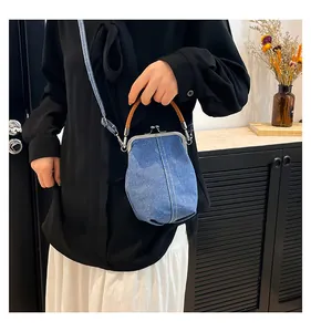 Detail of blue denim doctor bag with metal clasp and contrast white stitching accents