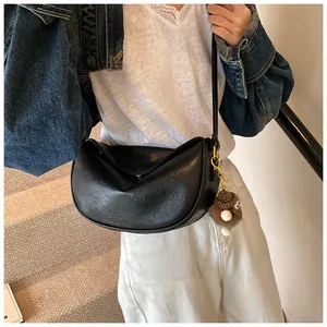 Detail of black pleated crescent bag with a brown plush monster charm on the zipper