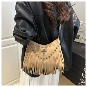 Detail view of khaki suede crossbody bag with metal studs, cross emblem and long tassels