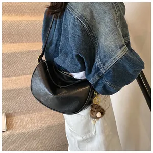 Detail of black pleated faux leather crescent bag with bear charm and gold hardware