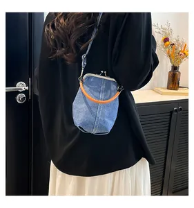 Blue denim shell bag with orange ring handle shown on a shoulder in a lifestyle setting
