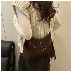 Detailed view of a brown suede bag featuring silver rivets, fringe and a skull logo
