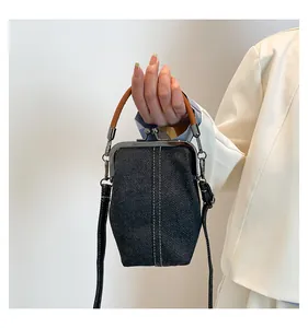 Close-up of vintage denim shell bag with white stitching and leather handle
