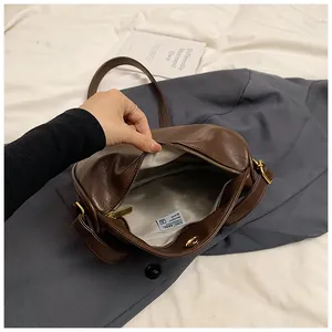 Close-up of dark brown vintage dumpling bag showing interior lining and metal zipper