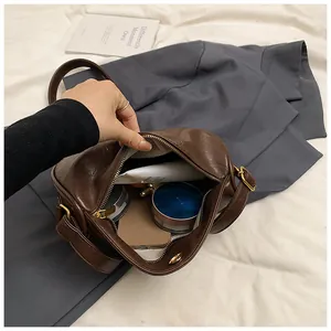 Interior capacity detail of dark brown leather crossbody bag with items and zipper closure
