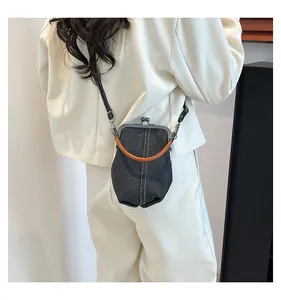 Detail of denim shell bag with orange handle and metal clasp on white blazer