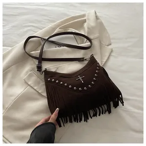 Detail of dark brown suede crossbody bag with vintage rivets and long fringe tassels