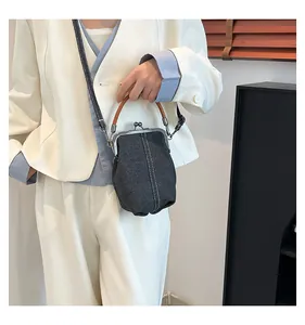 Detail of vintage denim shell bag featuring silver metal frame and brown rounded handle