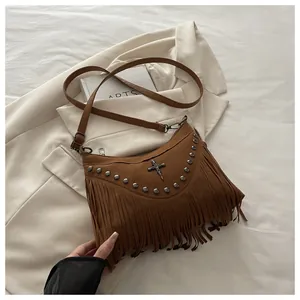 Detailed shot of brown suede crossbody bag with metal rivets, skull charm and long tassels