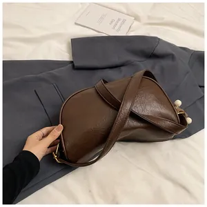 Detail of dark brown semi-circle PU leather bag with decorative charms and gold hardware