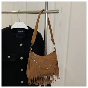 Close-up of brown suede bag featuring silver rivets, cross pendant, and long tassels