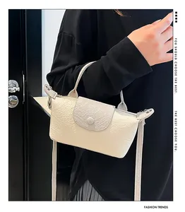 Detail of cream crossbody bag with crocodile leather texture and stylish round buckle