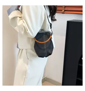 Detail of grey denim doctor bag featuring vintage metal frame and brown leather handle