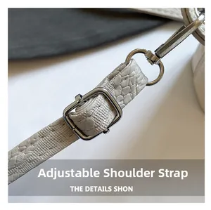 Detail of adjustable shoulder strap with silver hardware on faux crocodile leather bag