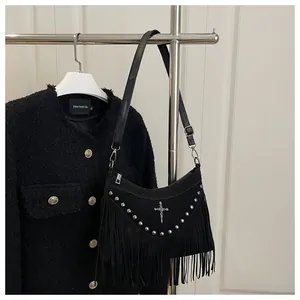 Close-up of black fringe shoulder bag with silver studs and metal cross pendant details