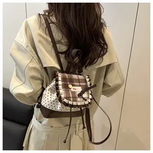 Detail of star-patterned mini backpack with brown plaid ruffles and cherry logo label