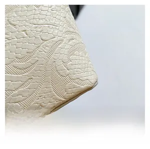 Detail of embossed crocodile texture and floral pattern on cream leather handbag