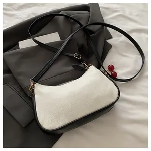 Detail of a chic monochrome crescent bag with leather texture and cherry charm accessory