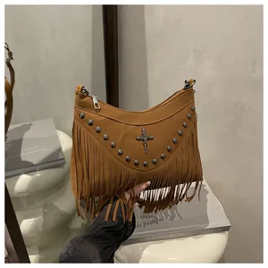 Detail of a brown fringe crossbody bag with silver rivets and metal cross pendant