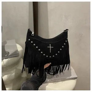 Detail of gothic black suede bag featuring metal studs, cross charm and long tassels