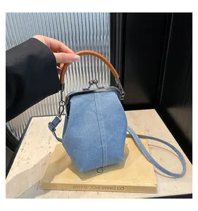 Detailed close-up of blue denim shell bag with silver metal clasp and brown top handle