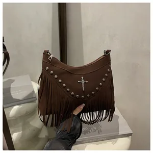 Close-up of brown suede bag with silver studs, cross pendant, and long fringe details