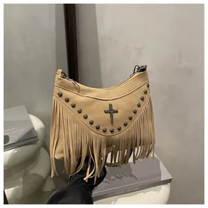 Detail of camel suede handbag featuring bohemian fringe, metal studs and cross emblem