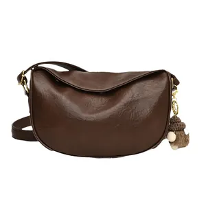Retro dark brown half-moon crossbody bag with premium leather texture and pompom charm