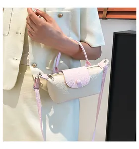 Detail of cream embossed leather mini bag with pink handles and detachable shoulder strap