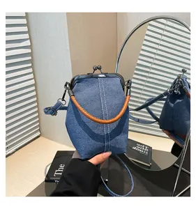 Detail of vintage denim shell bag with metal clasp and brown leather ring handle