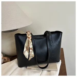 Detailansicht der schwarzen Ledershopper-Tasche mit elegantem Tuch auf Holzfläche