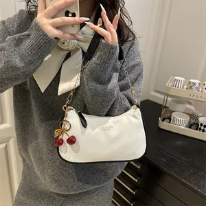 White hobo shoulder bag with black trim and cherry charm in lifestyle mirror selfie