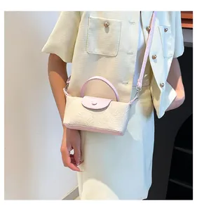 Detail of a chic cream embossed crossbody bag with pink accents on a female model