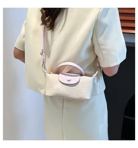 Detail of cream crossbody bag with pink handle and elegant floral embossed pattern