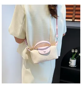 Detail of floral embossed cream and pink crossbody bag with adjustable strap and top handle